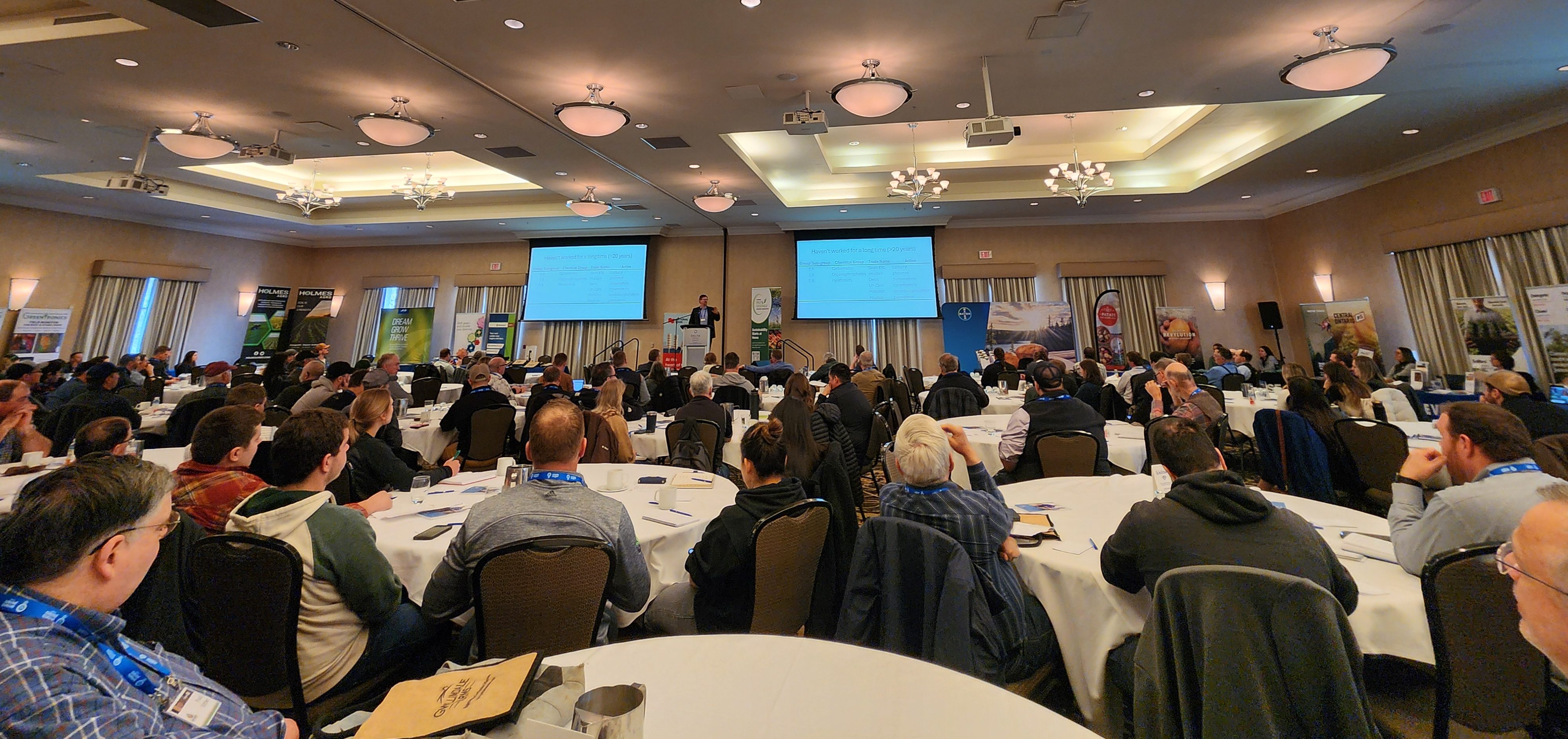 conference attendees listening attentively as a speaker presents their talk on potato research